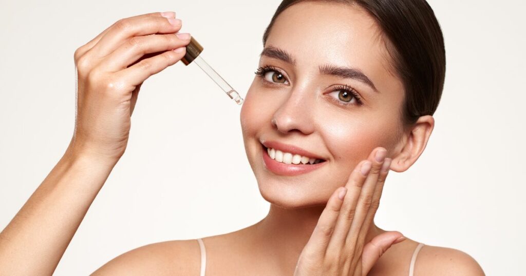 A woman applying face serum by patting gently with her hands